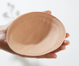 Beige silicone bra pad held in a hand against a white background