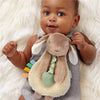 Baby holding a plush toy with colorful elements on a soft white background