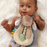 Baby holding a plush toy with colorful elements on a soft white background