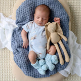 Newborn baby sleeping with a plush toy on a blue knit blanket
