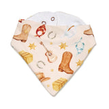 A triangular baby bandana bib with a western print featuring cowboy boots, horseshoes, stars, a guitar, and bales of hay on a cream background, with a white fleece lining.