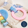 Baby toy with textured elements and a pink ring on a soft background