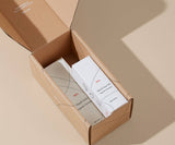 Open cardboard box with white boxes inside on a beige background