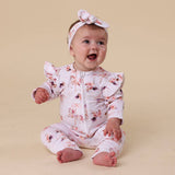 Baby wearing a floral outfit and headband on a beige background
