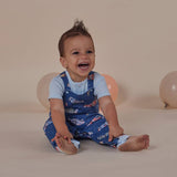 Baby wearing a blue outfit with car pattern sitting on a beige background