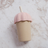 Two-toned cup with a pink lid and beige body on a marble surface