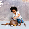 Child playing with wooden animal figurines on a gray surface