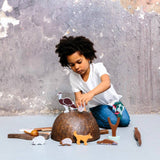 Child playing with wooden animal figurines on a gray surface