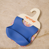 Blue baby bib on a hanger with 'rommer' branding on a beige background