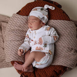 Newborn baby sleeping in a wooden crib with a knitted brown blanket