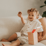 Child sitting on a couch holding a cookie with a box next to them