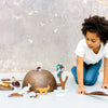 Child playing with wooden animal toys on a light surface with a neutral background