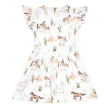 A white girls' dress with a watercolor-style western print featuring horses, cacti, and desert landscapes. The dress has ruffled cap sleeves, a round neckline, and a flared skirt, shown against a plain white background.