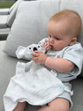 Baby holding a soft toy on a gray couch