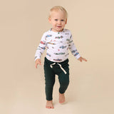 Child wearing a long-sleeve shirt with car prints and dark pants on a beige background