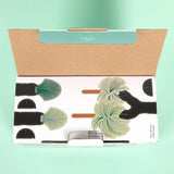 Flower-shaped packaging with a cardboard handle on a light green background