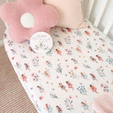 Crib sheet with fairy pattern and pink pillow on a crib