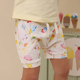 Child wearing colorful shorts with ice cream cone pattern in a room with ice cream-themed decor.