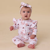 Baby wearing a floral outfit and headband on a beige background