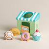 Toy bakery set with a striped roof and toy food items on a beige background