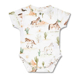 A short-sleeve baby bodysuit with a western desert print, featuring horses, cacti, and mountains on an off-white background. The bodysuit has snap closures at the neck and bottom.