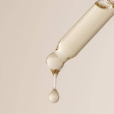 Skincare serum bottle with droplet on a beige background