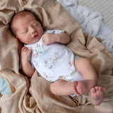 Newborn baby sleeping on a beige blanket with a patterned outfit