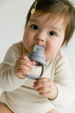 Baby holding a gray teething ring with a white background