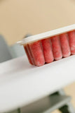 Red popsicles in a mold on a white surface with a blurred background