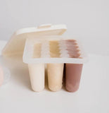 Popsicle mold with three popsicles in different colors on a light gray background