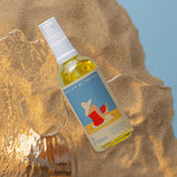 Bottle of 'Oil for Babies' by Willow by the Sea on a textured surface with a blurred natural background