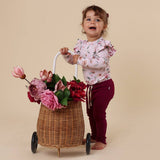 Child pushing a cart with flowers against a beige background