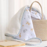Baby blanket with animal prints draped over a woven basket on a light background