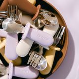 Set of children's cutlery with purple handles on a plate
