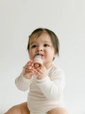 Baby holding a pink and gray toy against a white background