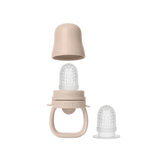 A beige baby teething ring with a clear silicone textured insert and a matching beige cap, shown on a plain white background with an additional clear silicone piece beside it.