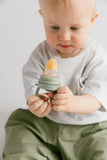 Child holding a green baby teether against a plain background