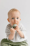 Baby holding a teething ring against a plain background