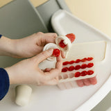 Person using a silicone mold to shape red gummy bears into a specific pattern.
