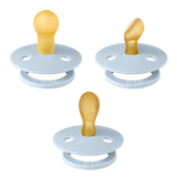 Three baby pacifiers on a plain white background, featuring light blue silicone shields with the brand name 'KUBA' embossed on the lower rim and translucent golden-yellow silicone nipples.