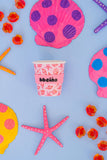 Paper cup with sea-themed design surrounded by colorful sea-themed decorations on a blue background
