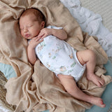 Newborn baby sleeping in a crib with beige bedding
