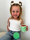 Young girl holding a green cup with snacks against a plain background