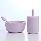 Purple bowl with spoon and purple tumbler with straw on a white background