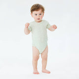 Baby wearing a green checkered onesie on a white background