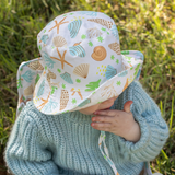 Child wearing a colorful shell-patterned sun hat outdoors