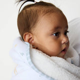 Baby wrapped in a white blanket with a neutral background