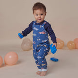Child wearing a blue patterned outfit with balloons in the background