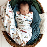 Newborn baby wrapped in a blanket with vehicle pattern in a wicker basket