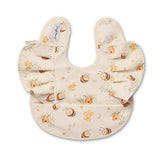A cream-colored baby bib with a playful print of cartoon bees, honeycombs, and small flowers. The bib features ruffled edges and a small fabric brand tag on the inside left side.